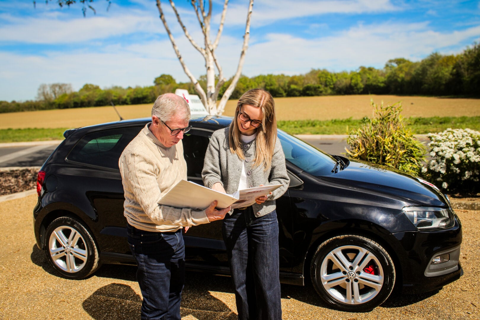 Driving instructor with learner by a car