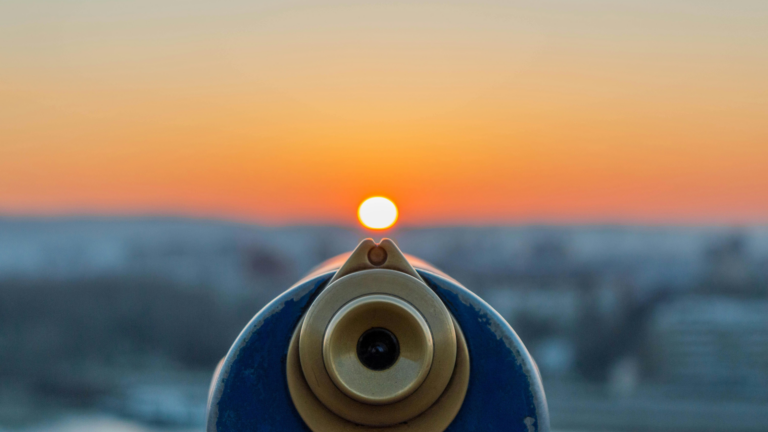 A telescope looking at a sunset over a city