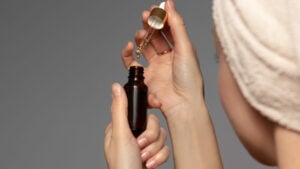lady using a bottle of skincare serum