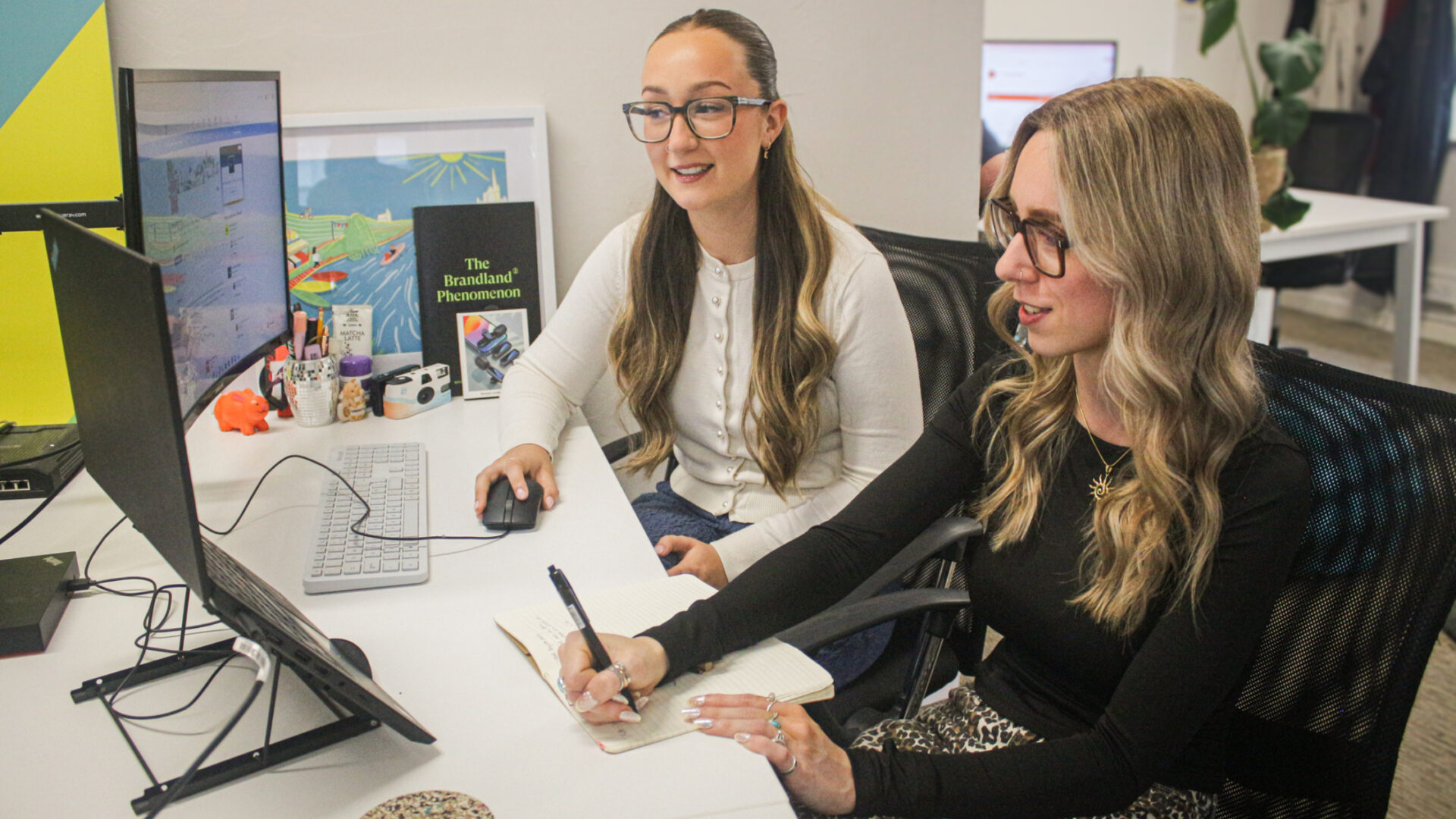 Aimée and Grace from the Yawn team working together at their desk in a modern, colourful office