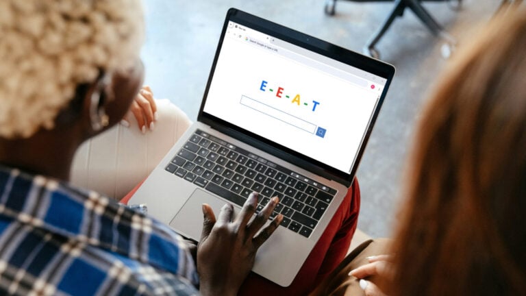Two people leaning over a laptop with a search engine on the screen